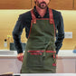 Fleur Du Bien eco-friendly apron styled in minimalist French kitchen setting. Fleur Du Bien eco-friendly apron worn by a man in the kitchen, also for barbecuing, gardening, and landscaping outdoors, showcasing adjustable straps and multiple pockets