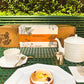 Fleur Du Bien Loose Leaf Green Tea & Herb Garden Kit box with stainless steel strainer and lemon cake, styled on luxurious Dior-inspired Parisian table setting